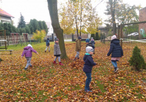 Dzieci biegają na terenie ogrodu przedszkolnego.